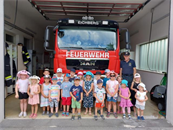 eine Gruppe von Kindern, die vor einem Feuerwehrauto für ein Foto posieren
